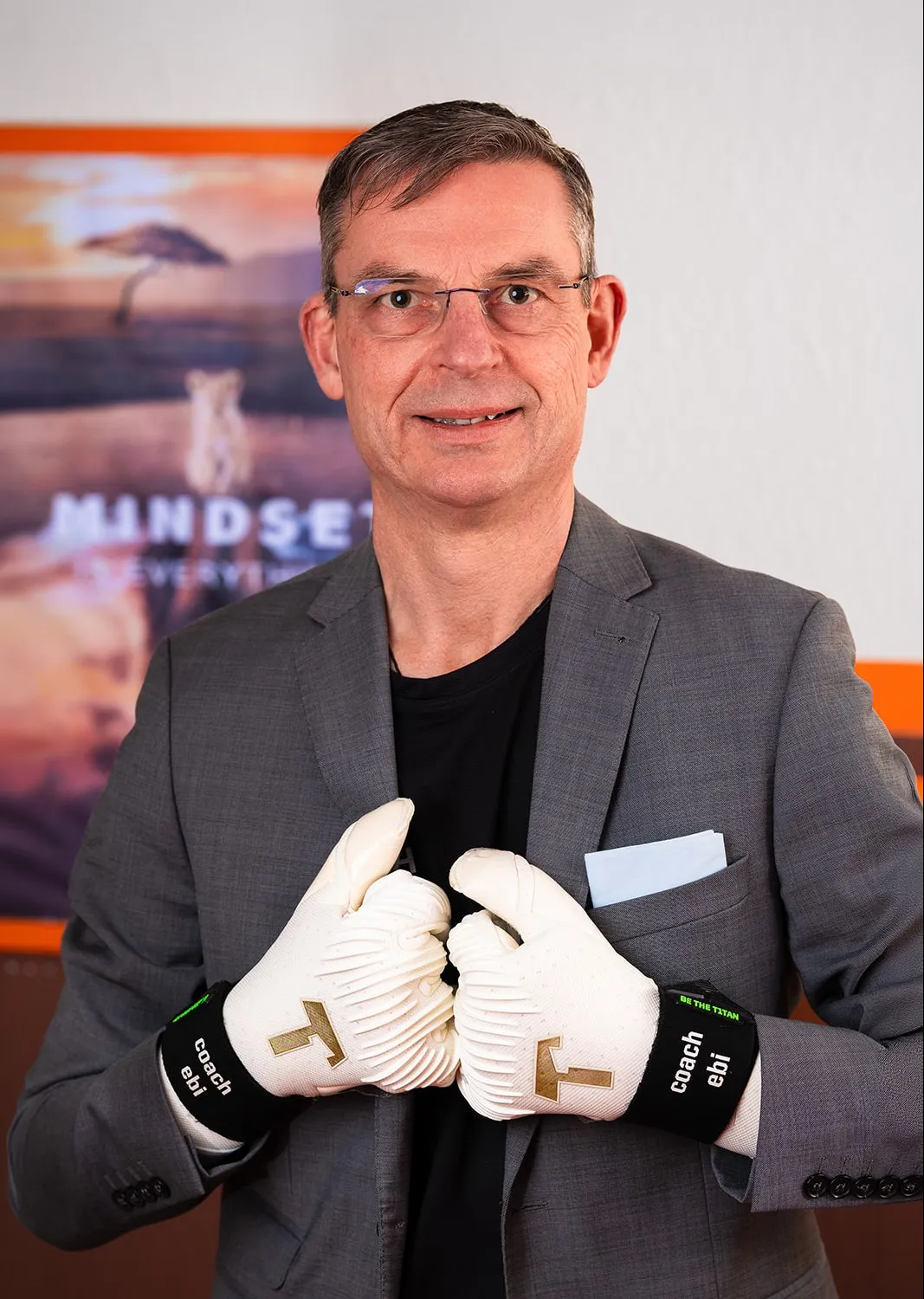 Markus Ebi im Sakko, beide Torwarthandschuhe mit dem Aufdruck „coach ebi“ vor der Brust.