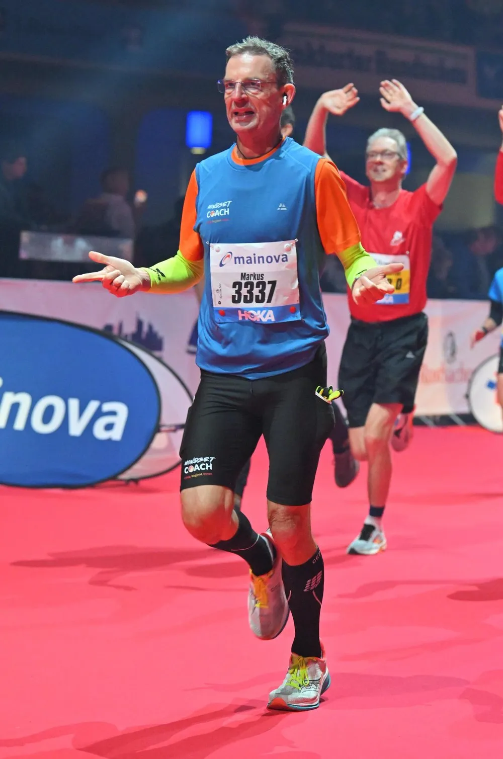 Markus Ebi beim Zieleinlauf eines Halbmarathons auf rotem Teppich, im Trikot mit dem Aufdruck „erfolg beginnt innen“.