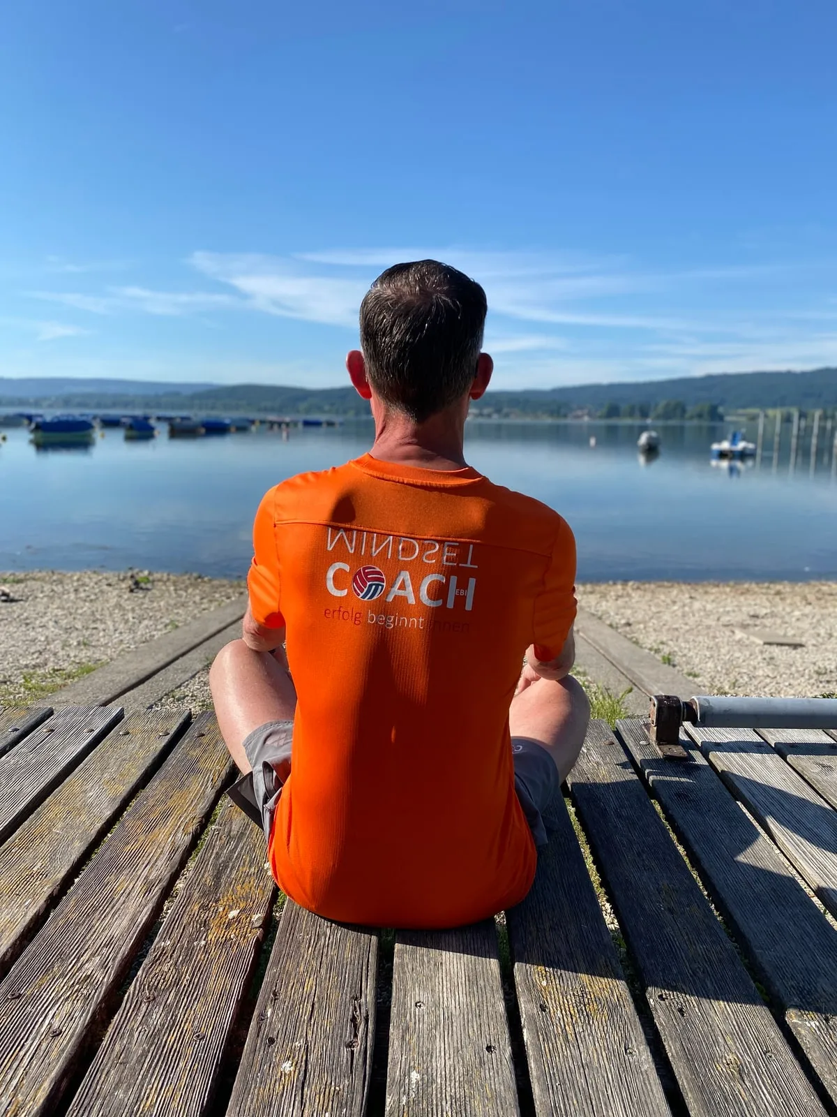 Markus Ebi sitzt allein am Ende eines Holzstegs und blickt über den See.
